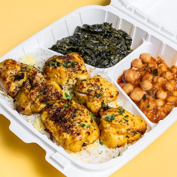 Sheesh Grill's chicken and rice platter with spinach and chickpeas in a takeout container.