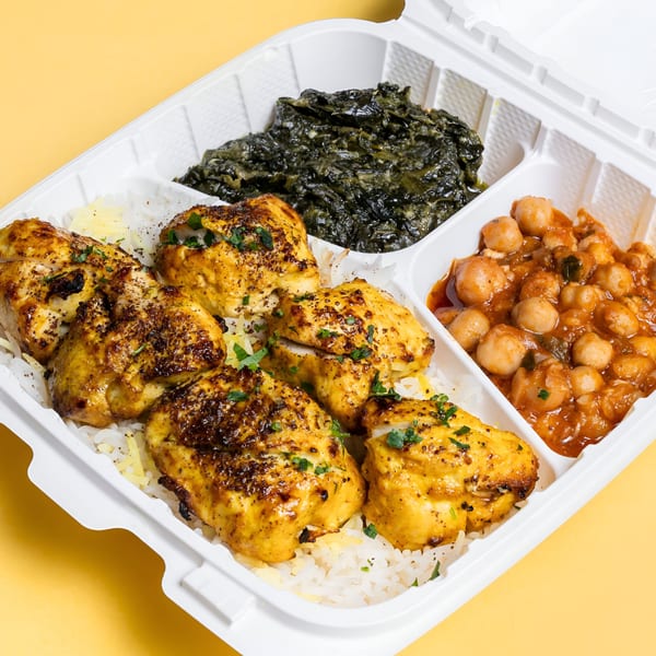 Sheesh Grill's chicken and rice platter with spinach and chickpeas in a takeout container.