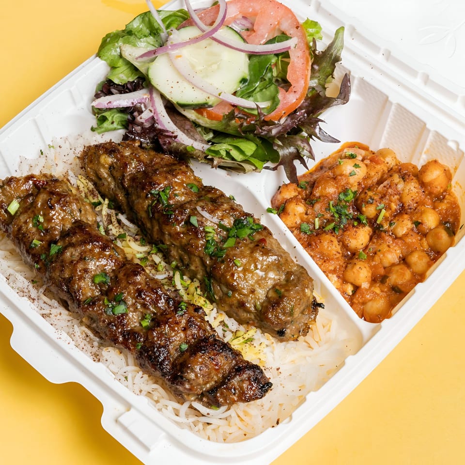 Sheesh Grill's kofta kebab meal with rice, chickpea stew, and a fresh salad in a takeout container.