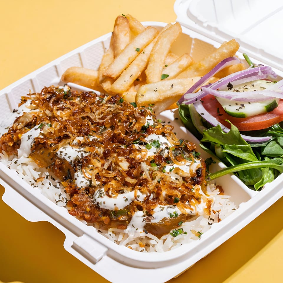 Middle-Eastern meal with rice, meat, fried onions, fries, and a side salad in a takeout container.